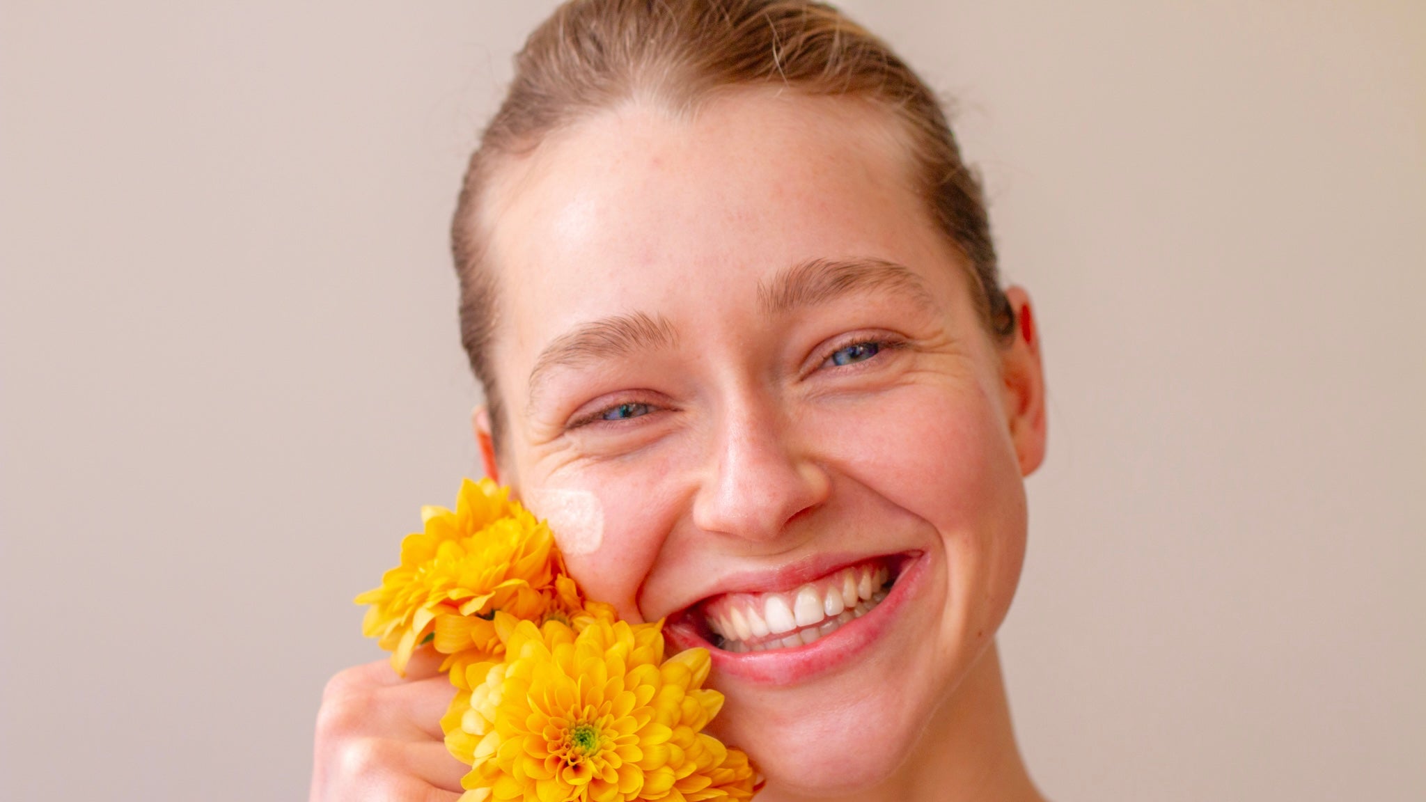 Smiling woman with healthy-looking skin using VAÍAA natural tallow skincare.